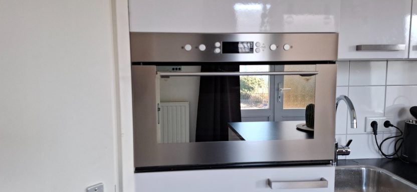 Ingebouwde oven met een glazen deur in een moderne keuken.