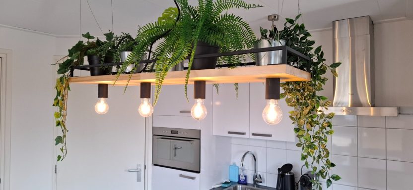 Hangende lamp met planten in een keukeneiland, met vier lichtbronnen en modern ontwerp.