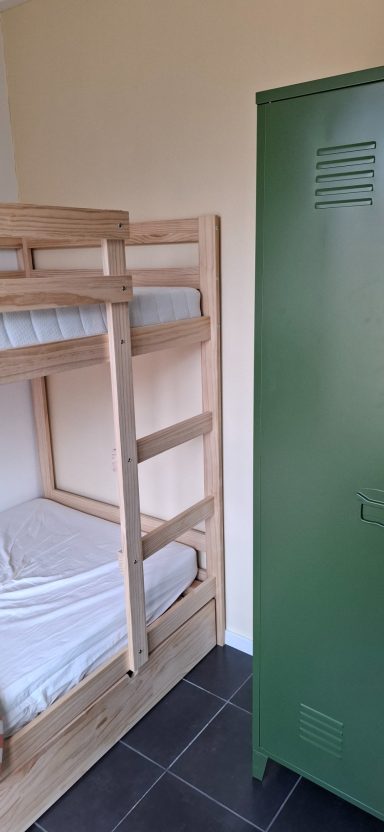 Stapelbed naast een groene kledingkast in een kamer.